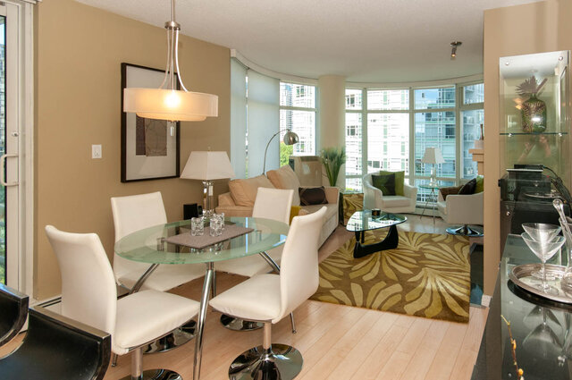 Modern dining area with glass table, white chairs, and city view. - 905 - 1199 Marinaside Cres., Vancouver Downtown