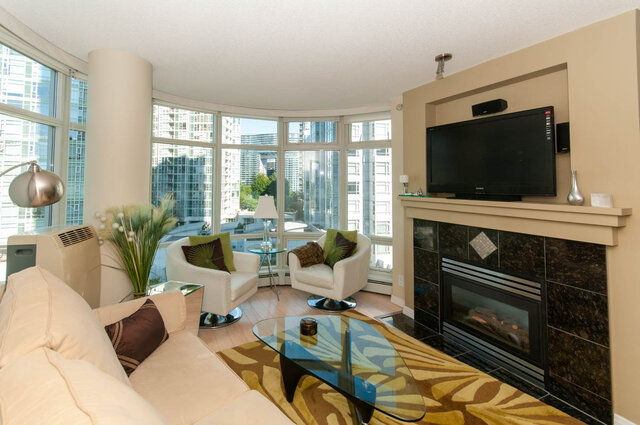 Spacious living room with a city view, modern fireplace, and comfortable seating. - 905 - 1199 Marinaside Cres., Vancouver Downtown