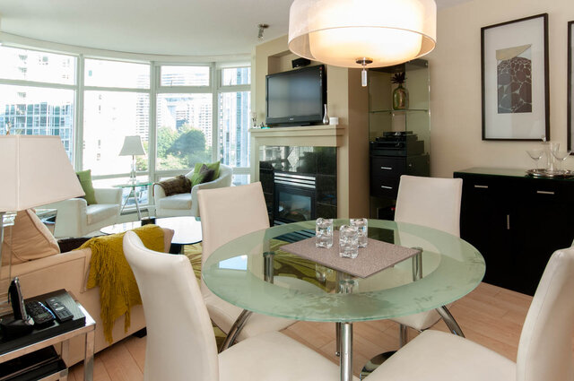 Spacious living room with modern furniture, large windows offering city views, and a sleek glass dining table.