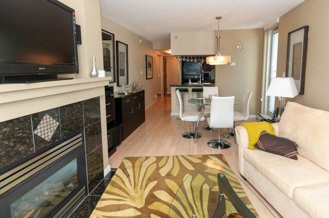 Spacious living room with modern furnishings, hardwood floors, and a cozy fireplace. - 905 - 1199 Marinaside Cres., Vancouver Downtown