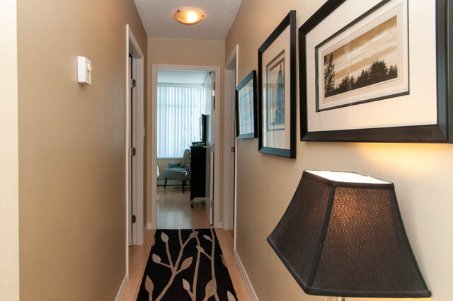 Spacious hallway with framed artwork and a cozy corner desk, leading to a well-lit living area. - 905 - 1199 Marinaside Cres., Vancouver Downtown
