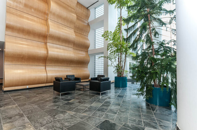 Spacious living room with modern furniture, large windows, and a stylish wooden accent wall. - 905 - 1199 Marinaside Cres., Vancouver Downtown