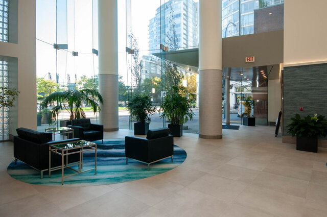 Spacious living room with large windows, modern furniture, and a city view. - 905 - 1199 Marinaside Cres., Vancouver Downtown