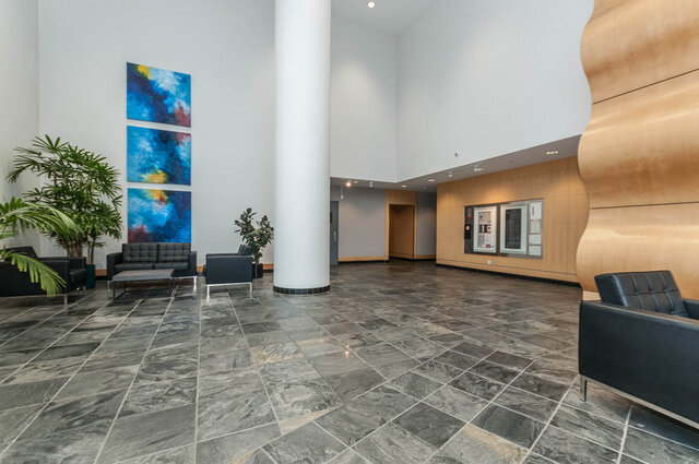 Spacious living room with modern furniture, marble floors, and vibrant abstract art. - 905 - 1199 Marinaside Cres., Vancouver Downtown