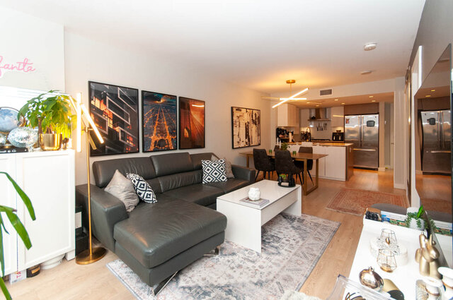 Spacious open-concept living room with modern furnishings, hardwood floors, and a cityscape art piece. - 1006 -1618 Quebec Street, Vancouver East Side