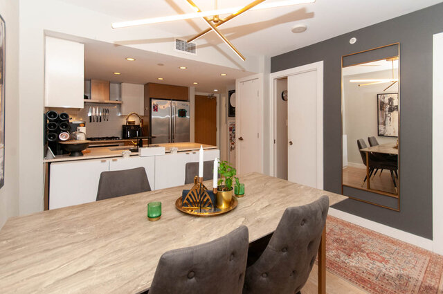 Spacious dining area with marble countertop and modern kitchen in a cozy, well-furnished 1-bedroom + den condo.