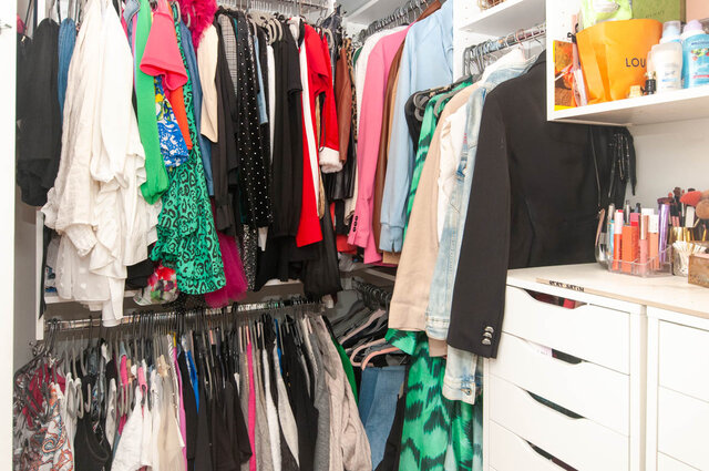 Spacious walk-in closet with neatly organized clothing and shelves, perfect for a 1-bedroom + den condo.