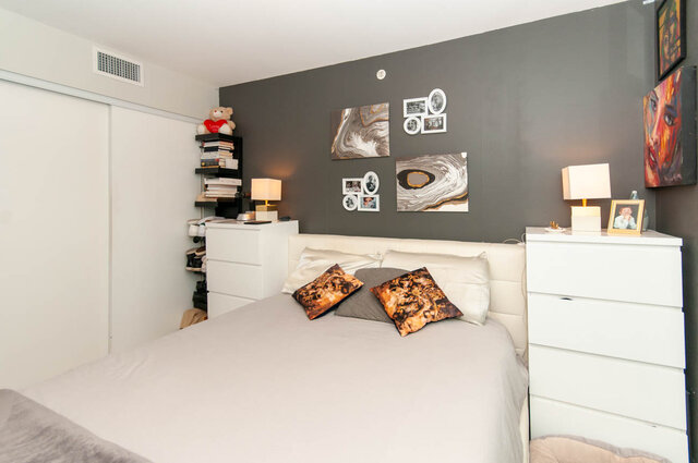 Spacious 1-bedroom + den with a cozy, modern vibe featuring a dark accent wall, stylish artwork, and a neatly arranged...