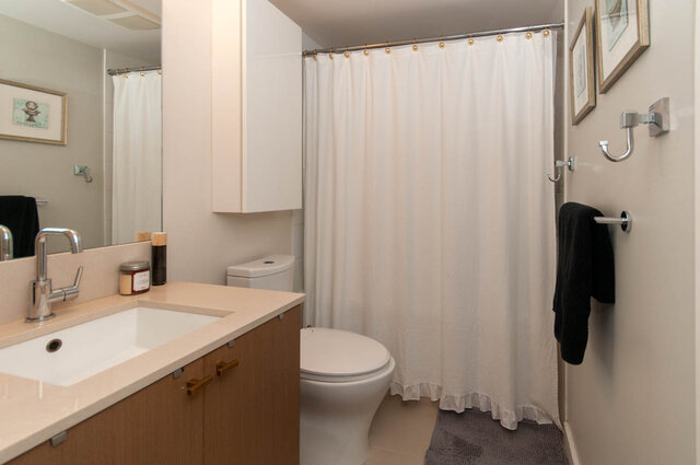 Spacious bathroom with white countertop, wooden cabinets, and a shower curtain. - 1006 -1618 Quebec Street, Vancouver East Side