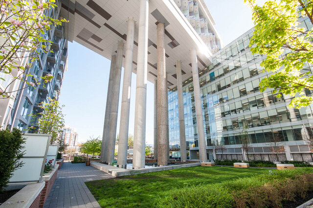 Spacious living room with modern glass facade and lush green courtyard. - 1006 -1618 Quebec Street, Vancouver East Side