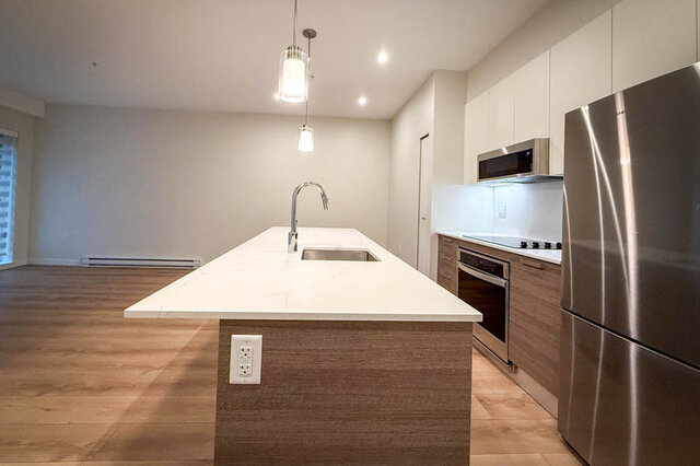 kitchen with stainless steel appliances, hardwood floors, white countertops, small window, and central island sink