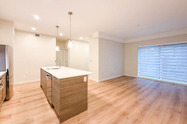 kitchen with central island, stainless steel refrigerator and dishwasher, hardwood floors, and large window
