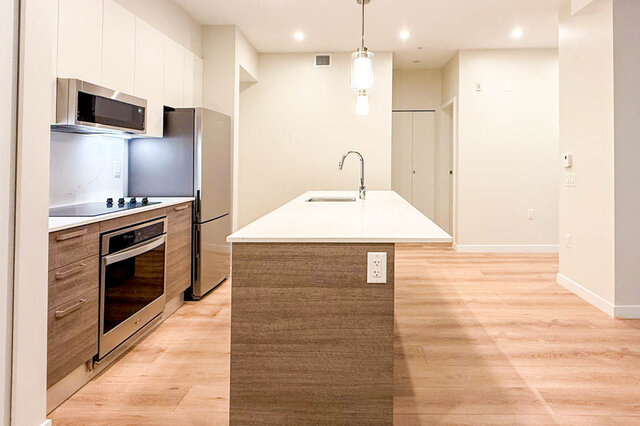 kitchen with stainless steel appliances, white countertops, hardwood floors, and an island sink - G 3- 2030 East 20th Ave, Vancouver East Side
