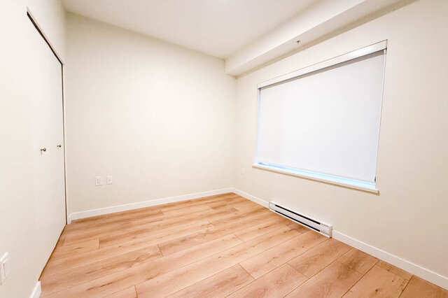 This is a bedroom with hardwood floors, a window with roller shade, and a baseboard heater. - G 3- 2030 East 20th Ave, Vancouver East Side