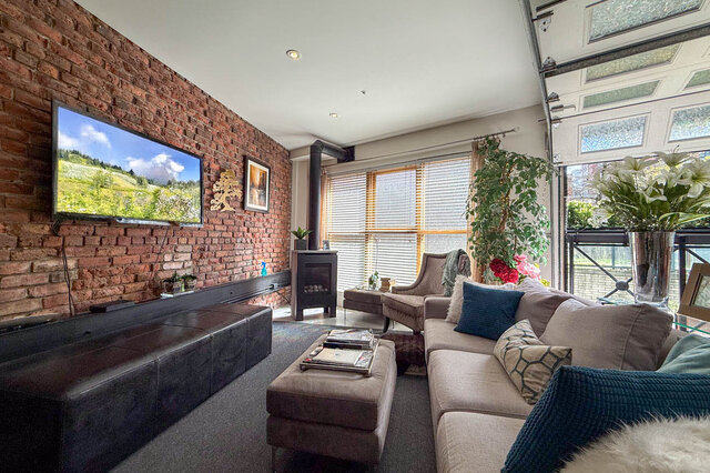 Spacious living room with exposed brick wall, modern furniture, and large windows. - 202 - 1230 Hamilton Street, Vancouver Downtown