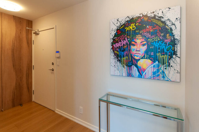 Bright hallway with hardwood floors and a vibrant graffiti-style artwork featuring a colorful portrait. - 3006 - 33 Smithe Street, Vancouver Downtown