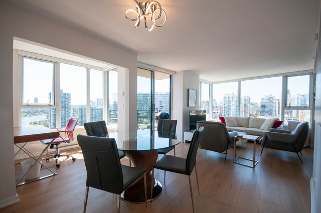 Spacious living room with hardwood floors, a modern glass dining table, and stunning city views. - 3006 - 33 Smithe Street, Vancouver Downtown
