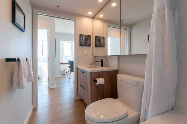 Modern bathroom with white countertops, wooden floors, and a city view. - 3006 - 33 Smithe Street, Vancouver Downtown