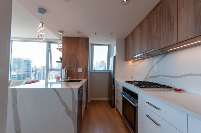 Bright kitchen with white marble countertops, hardwood floors, and a city view. - 3006 - 33 Smithe Street, Vancouver Downtown