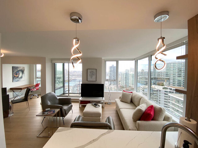 Spacious living room with hardwood floors, city view, and modern lighting fixtures. - 3006 - 33 Smithe Street, Vancouver Downtown