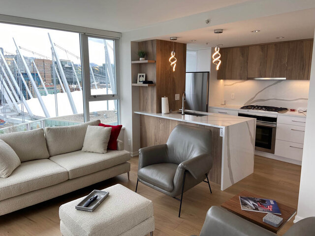 Modern open-concept living with hardwood floors, a large city view, and a sleek kitchen with white countertops and wooden...