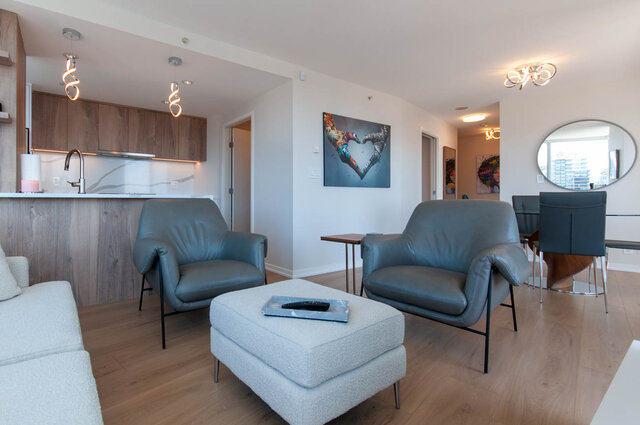 Spacious living room with modern furniture, hardwood floors, and a city view. - 3006 - 33 Smithe Street, Vancouver Downtown