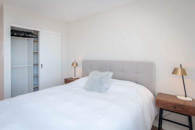 Spacious bedroom with a cozy bed, white linens, and a stylish grey upholstered headboard. - 3006 - 33 Smithe Street, Vancouver Downtown