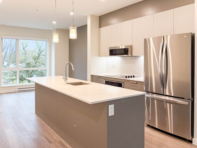 Bright kitchen with sleek white countertops, stainless steel fridge, and hardwood flooring. - TH 12 - 2030 East 20th Ave, Vancouver East Side