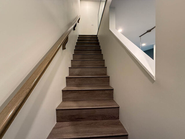 Staircase leading to upper level with wooden steps and modern railings, ideal for accessing the 3-bedroom townhouse.