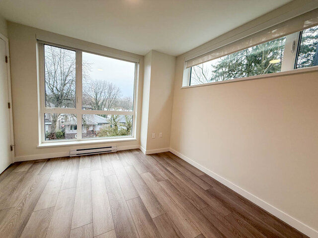 Bright living room with hardwood floors and large windows offering a city view. - TH 13 - 2030 East 20th Ave, Vancouver East Side