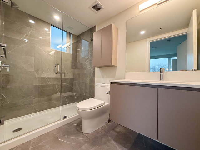 Modern bathroom with sleek vanity, large mirror, and glass-enclosed shower. - TH 13 - 2030 East 20th Ave, Vancouver East Side