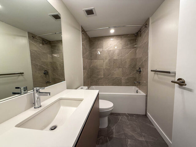 Modern bathroom with sleek white quartz countertop and marble-tiled shower area. - TH 12 - 2030 East 20th Ave, Vancouver East Side