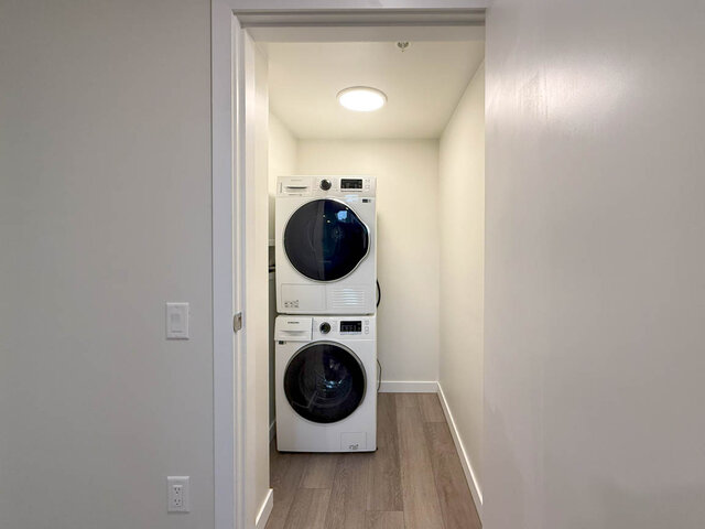 Compact laundry room with stacked washer and dryer, light wood flooring, and a modern design. - TH 13 - 2030 East 20th Ave, Vancouver East Side