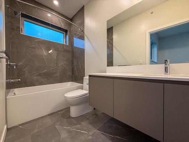 Modern bathroom with sleek white countertop and dark marble walls. - TH 13 - 2030 East 20th Ave, Vancouver East Side