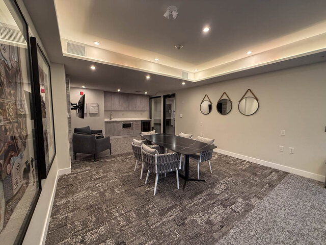 Modern dining area with a sleek black table, gray woven chairs, and wall-mounted mirrors. - TH 13 - 2030 East 20th Ave, Vancouver East Side