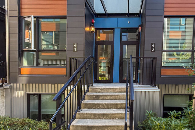 Modern townhouse entrance with sleek black railings and a vibrant blue door, perfect for a cozy 3-bedroom rental.