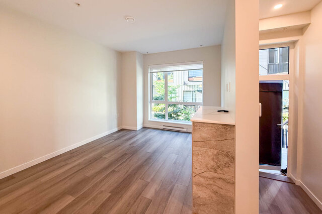 Spacious living room with hardwood floors and a large window offering a city view. - TH 46- 2050 East 20th Ave, Vancouver East Side