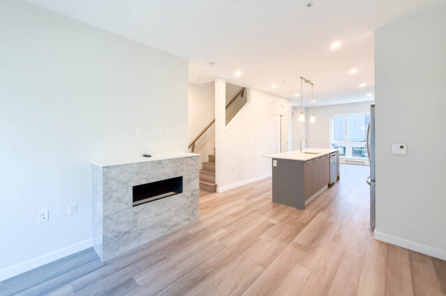 Open-concept living space with a modern fireplace and hardwood floors. - TH 46- 2050 East 20th Ave, Vancouver East Side
