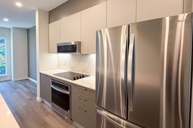 Modern kitchen with sleek stainless steel appliances, white marble countertops, and hardwood floors. - TH 46- 2050 East 20th Ave, Vancouver East Side