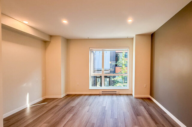 Spacious living room with hardwood floors and a large window offering a city view. - TH 46- 2050 East 20th Ave, Vancouver East Side
