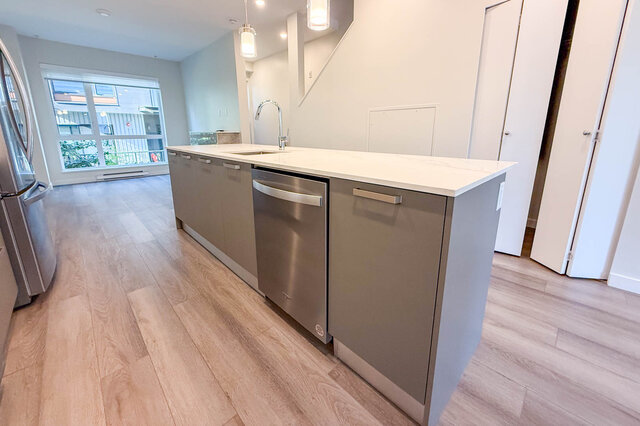 Modern kitchen with sleek white countertops, stainless steel dishwasher, and hardwood floors. - TH 46- 2050 East 20th Ave, Vancouver East Side