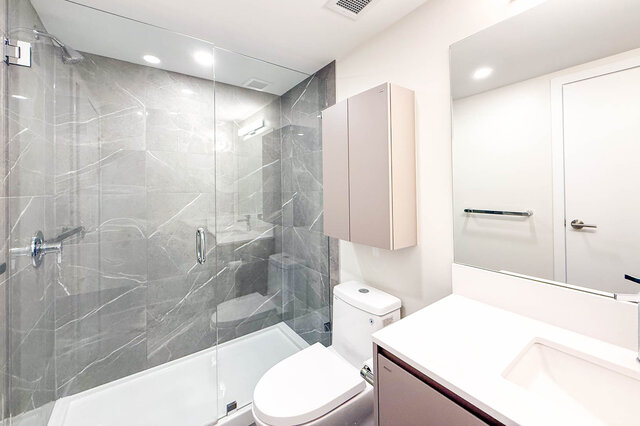 Modern bathroom with sleek white countertops and a glass-enclosed shower. - TH 46- 2050 East 20th Ave, Vancouver East Side