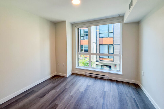 Spacious living room with hardwood floors and a large window offering a city view. - TH 46- 2050 East 20th Ave, Vancouver East Side