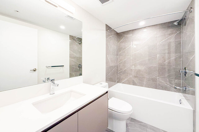 Spacious bathroom with modern white vanity, large mirror, and sleek bathtub. - TH 46- 2050 East 20th Ave, Vancouver East Side