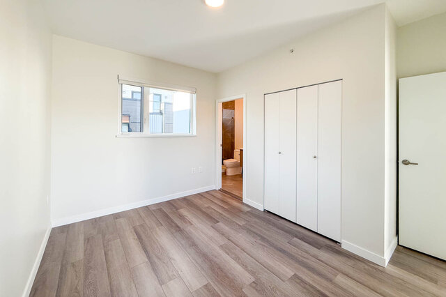 Spacious bedroom with hardwood floors, large closet, and natural light from a window. - TH 46- 2050 East 20th Ave, Vancouver East Side