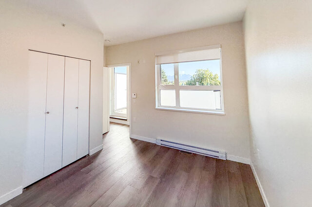 Bright living room with hardwood floors and a large window offering a city view. - TH 46- 2050 East 20th Ave, Vancouver East Side