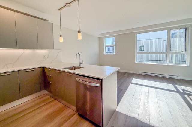 Bright modern kitchen with white quartz countertops and light wood flooring. - 400 - 3588 Hull St, Vancouver East Side