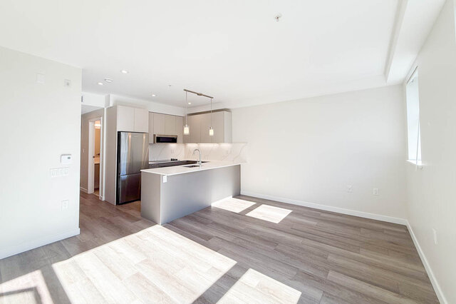 Bright living space with light wood flooring and large window with white blinds. - 400 - 3588 Hull St, Vancouver East Side
