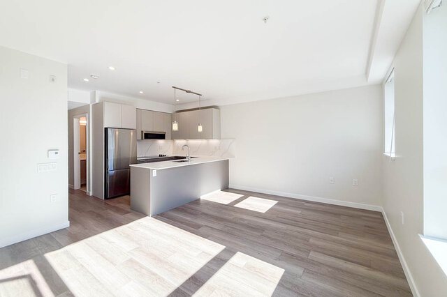 Bright kitchen with white quartz countertops and light wood hardwood floors. - 400 - 3588 Hull St, Vancouver East Side
