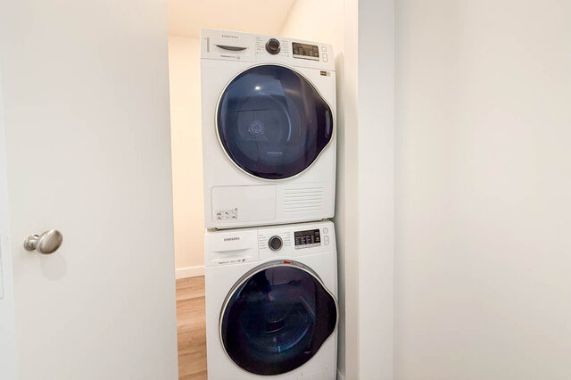 Laundry room with Samsung stacked washer-dryer and hardwood flooring. - 400 - 3588 Hull St, Vancouver East Side